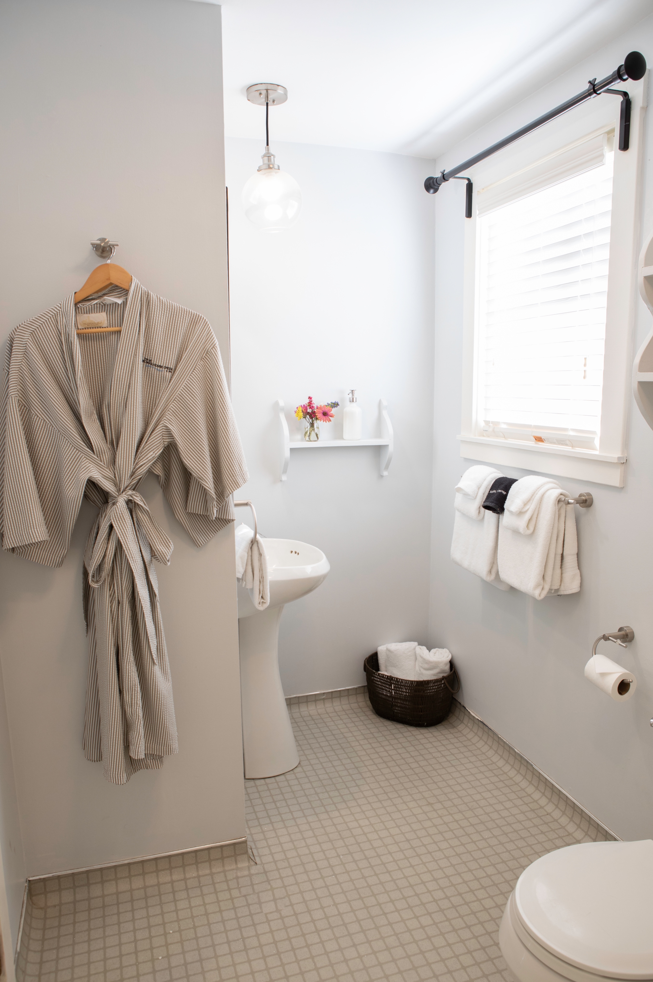 Clean and bright bathroom with a robe hanging on the wall.