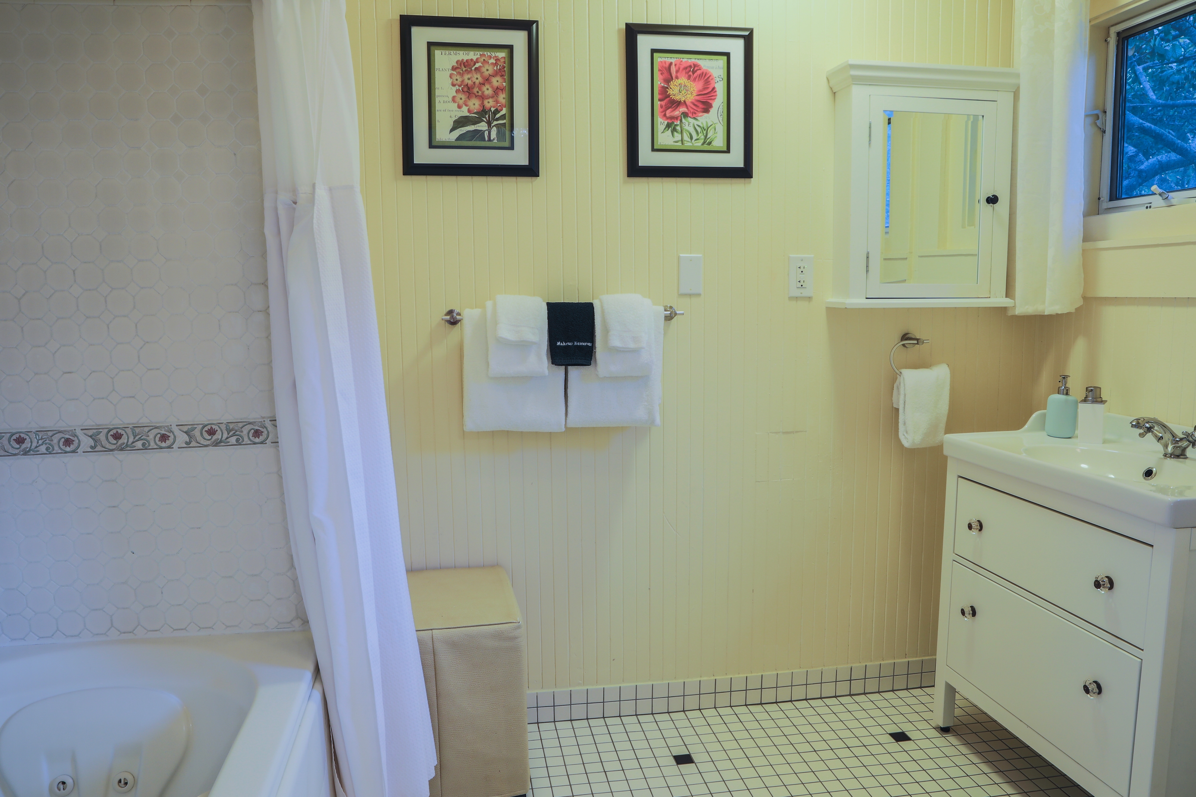 A clean and spacious bathroom with a white bathtub, a white sink, and a toilet. Two towels hang on a rack on the wall.