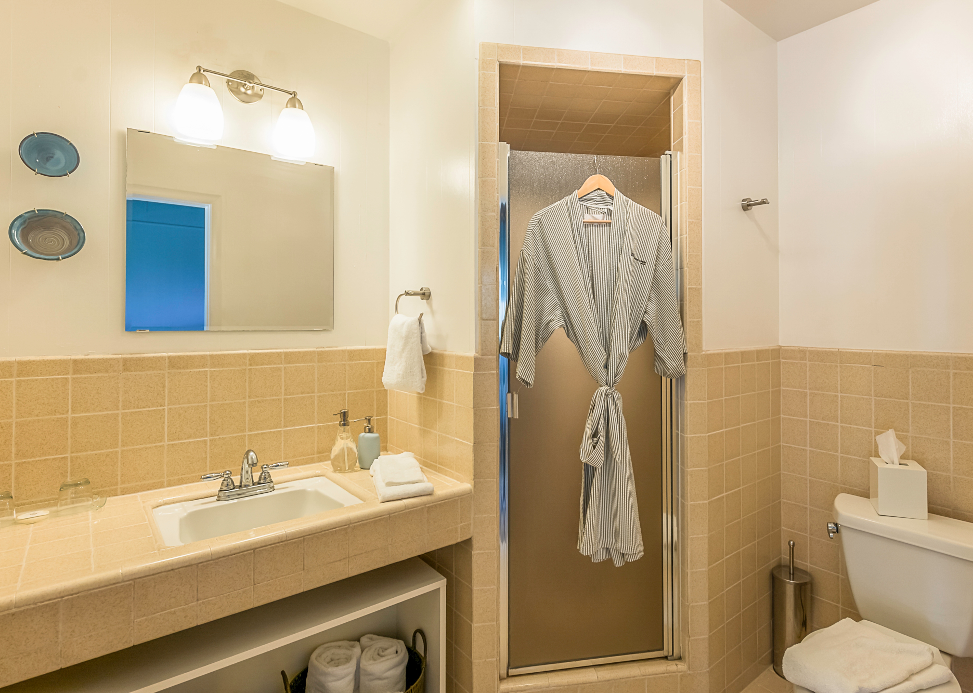 Anderson Valley bathroom with a sink, toilet, and shower. A robe hangs on a hook beside the shower.