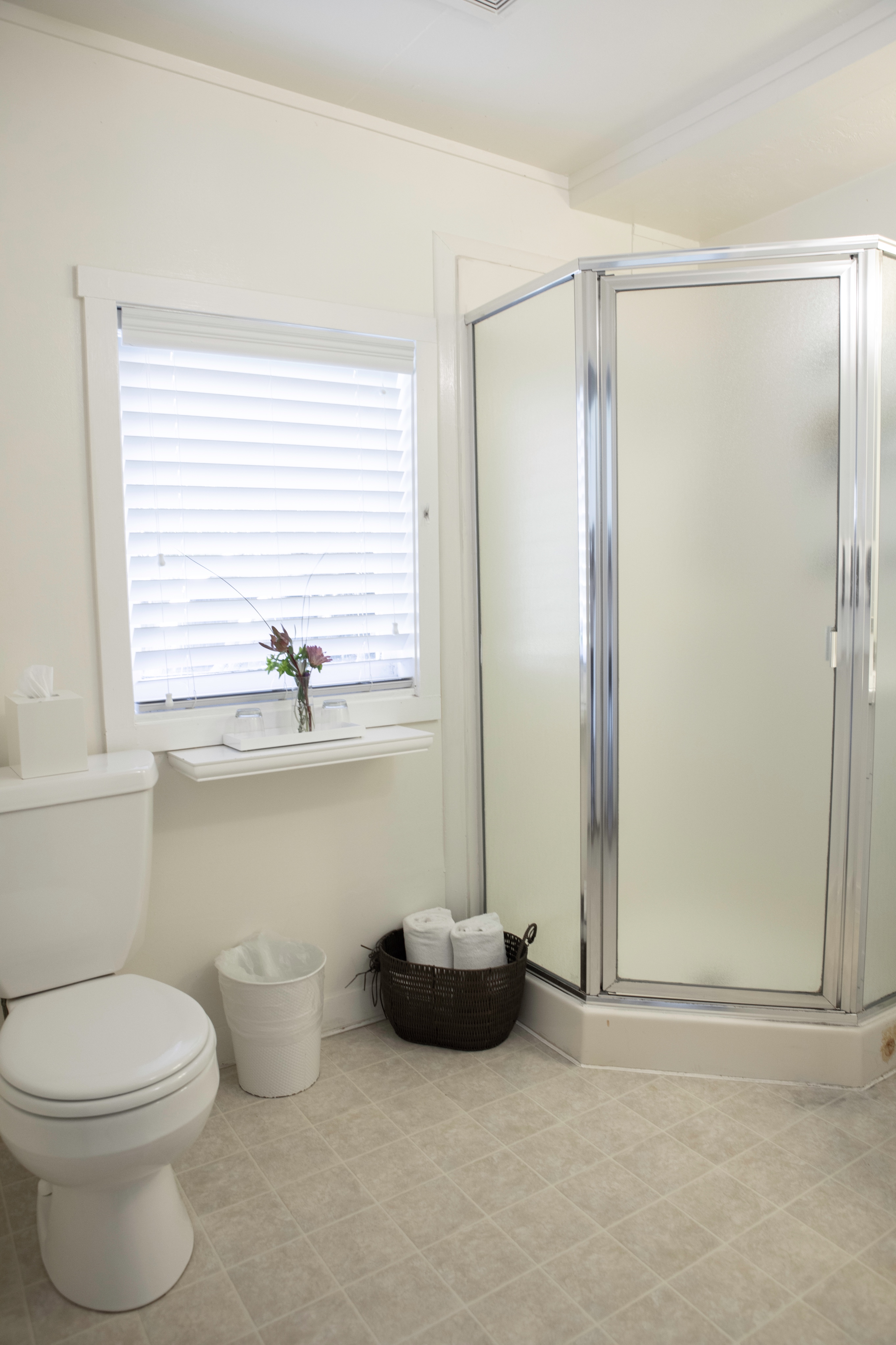 A bright and airy bathroom with a toilet, a sink, and a glass shower stall.