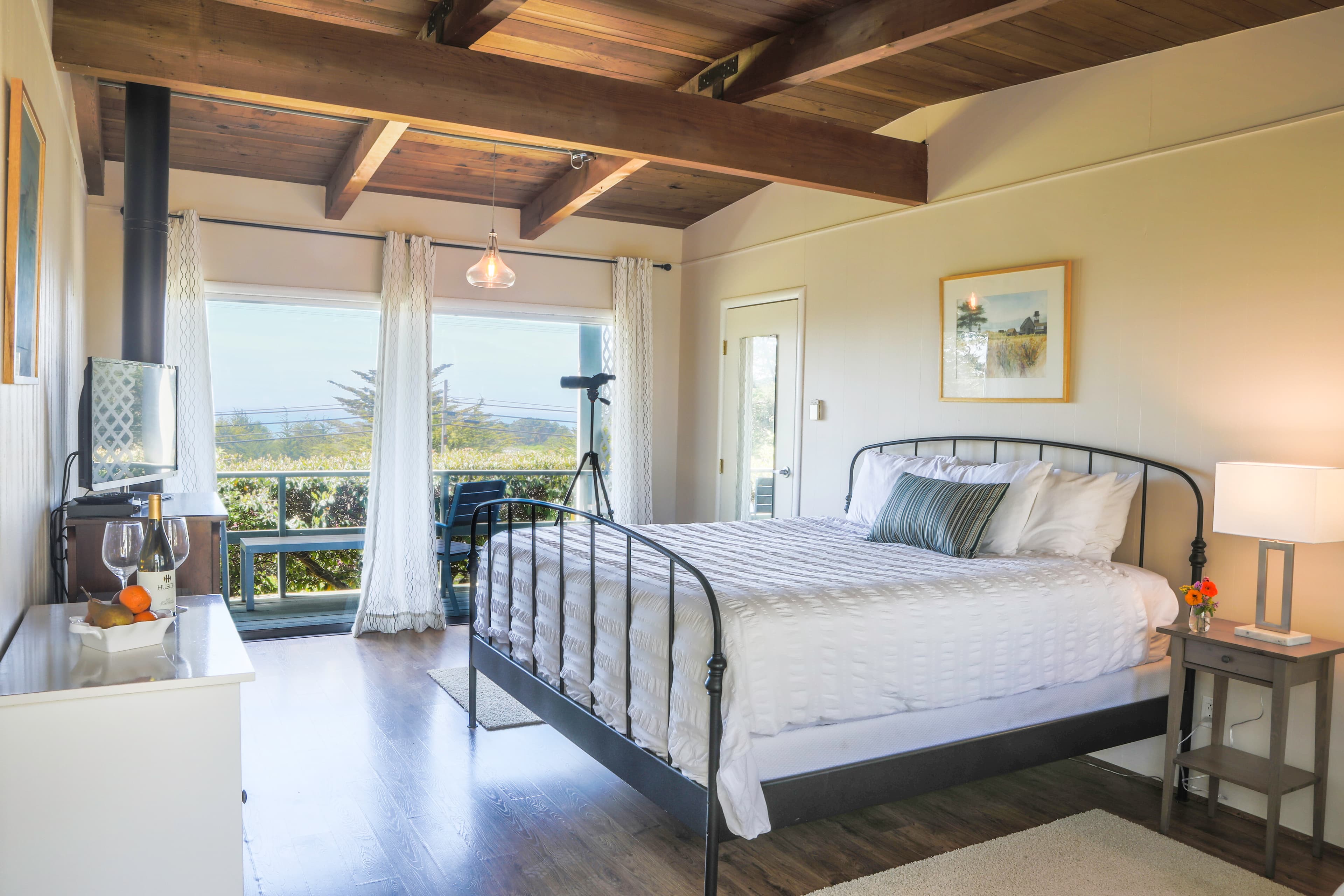 Bedroom with a king-sized bed, a wood-burning stove, and a view of the outdoors through large sliding glass doors.