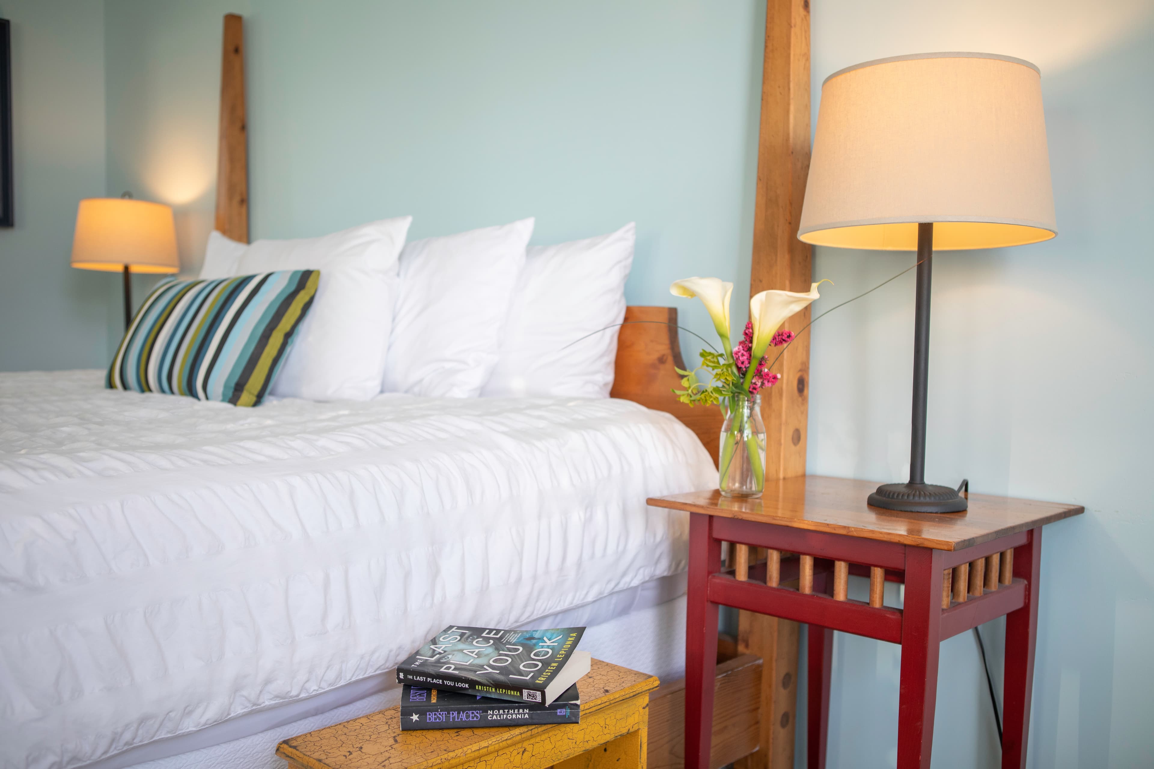 Bedroom with a king-sized bed, a nightstand, and a view of the outdoors through a window.