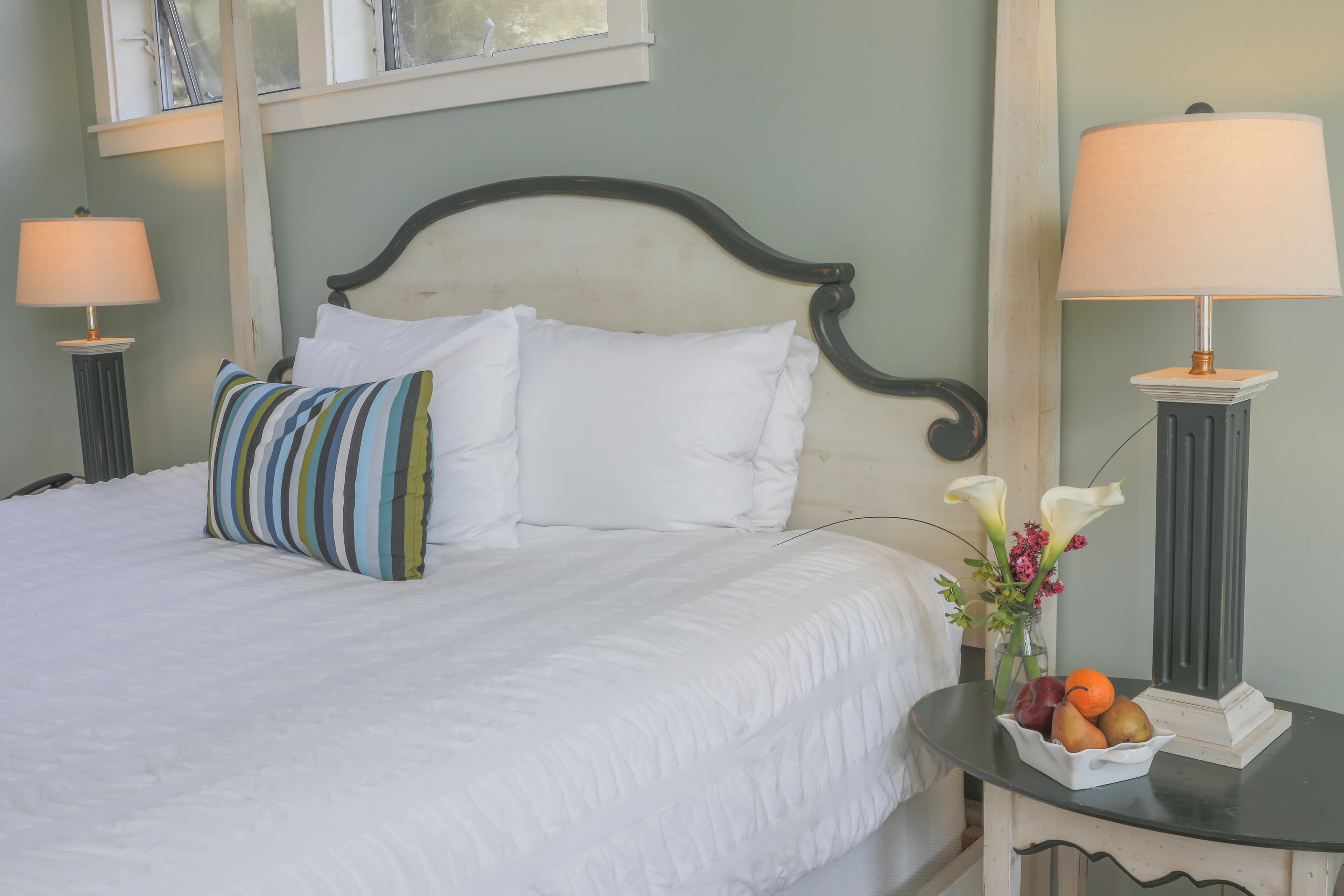 Pacific View bedroom with a king-sized bed, a nightstand, and a view of the outdoors through a window.