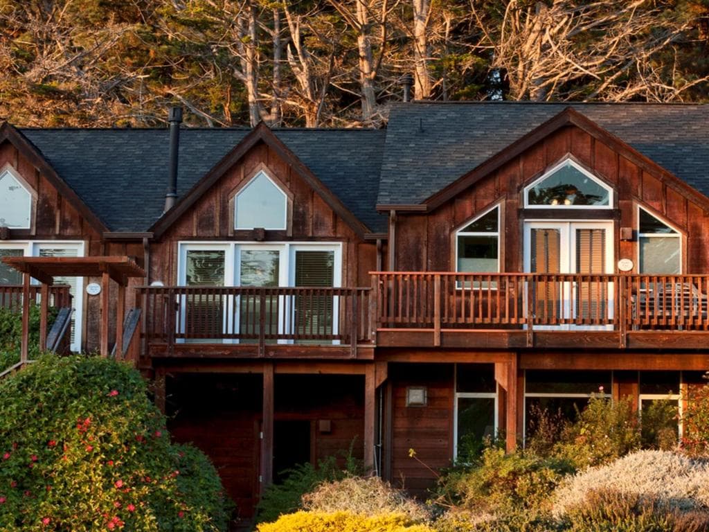 A rustic lodge with a wood-paneled exterior and multiple levels, surrounded by lush greenery.