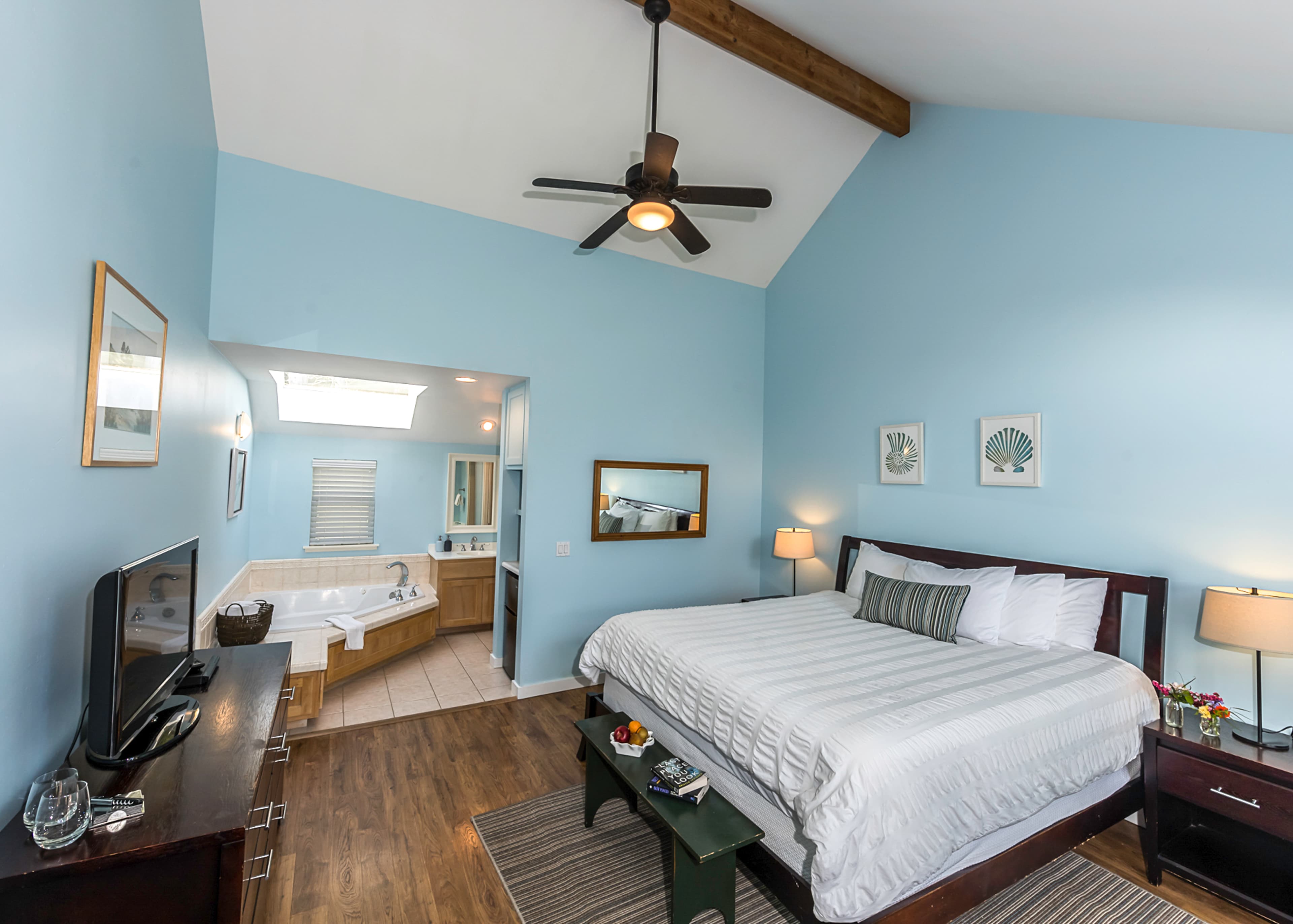 Whale Watch bedroom with a king-sized bed, a jetted tub visible in the background, and a ceiling fan.