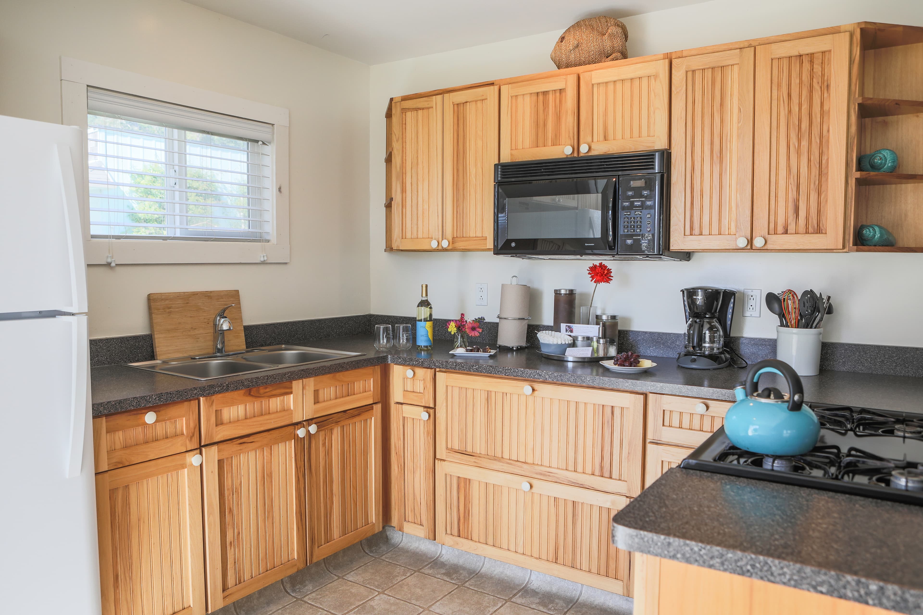 A small, well-equipped kitchenette with wooden cabinets, a stove, a refrigerator, and a microwave.