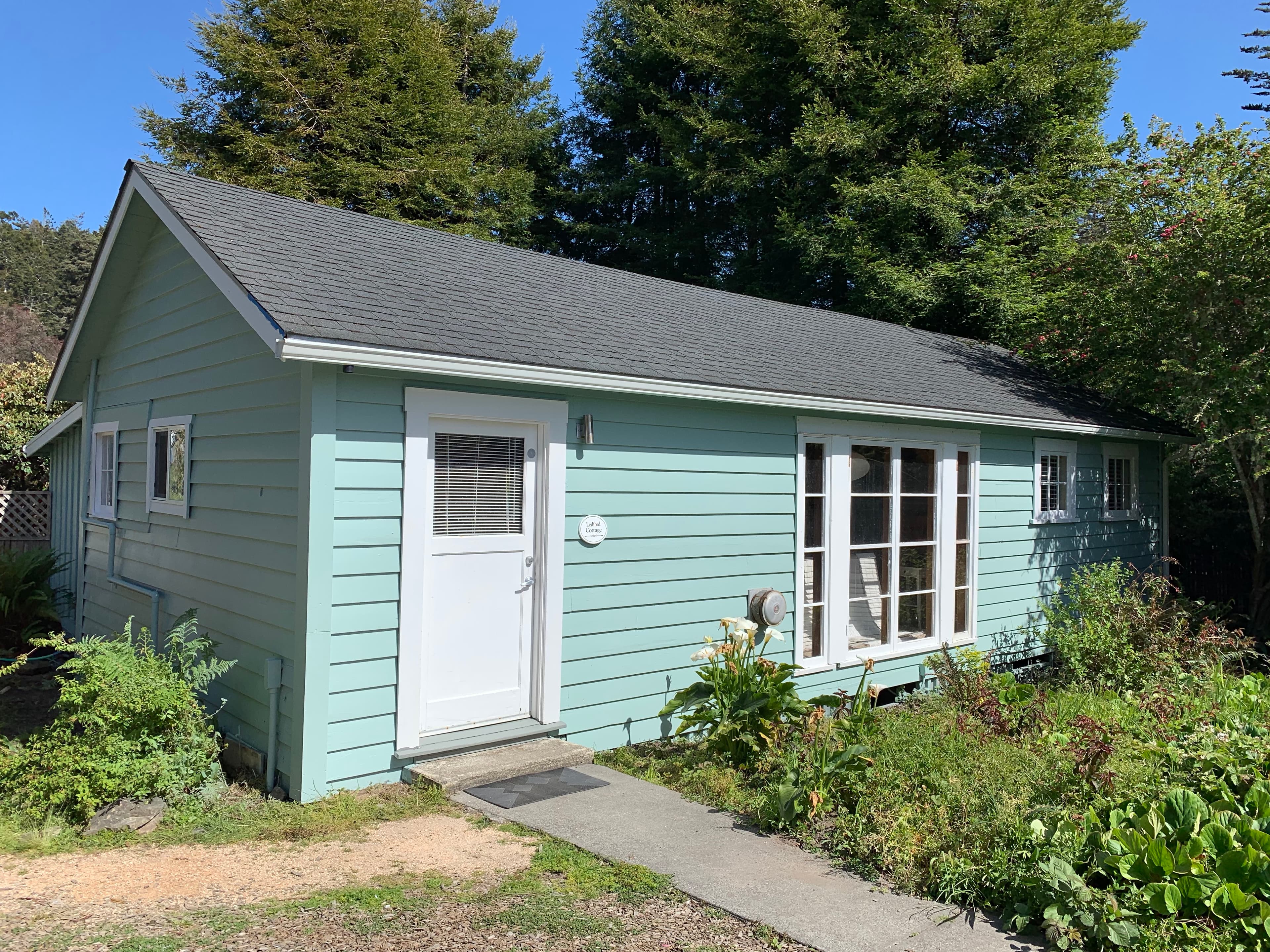 A small, light blue house with white trim and a white door.