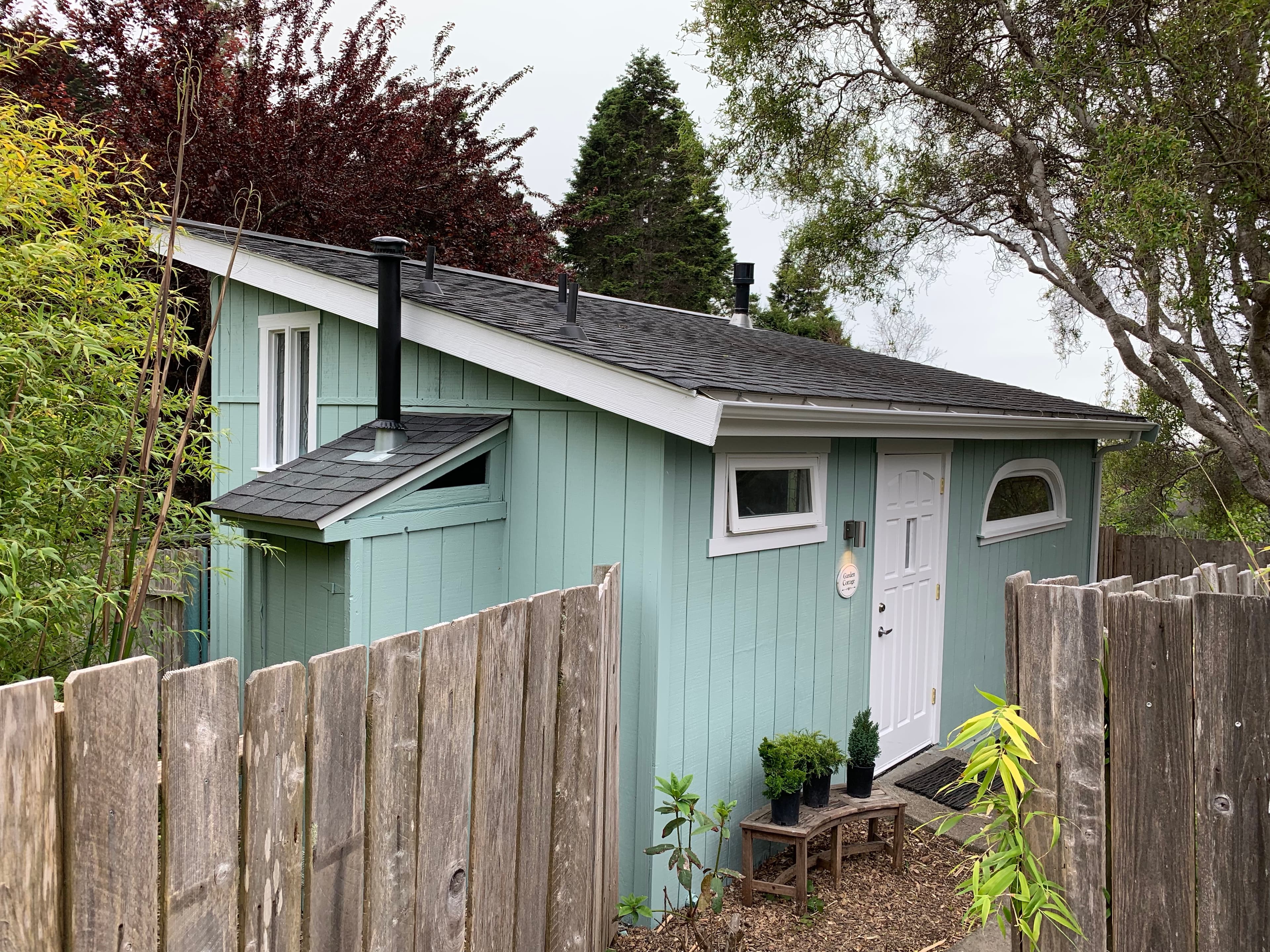 A small, quaint blue cottage with white trim and a white door.