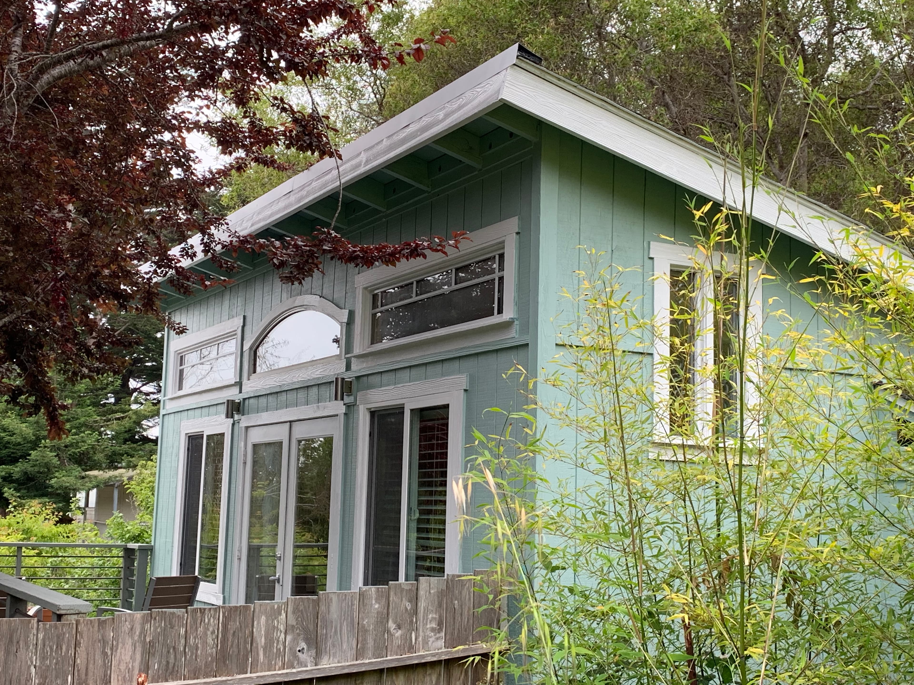 A small, light blue cottage with white trim and a white door.