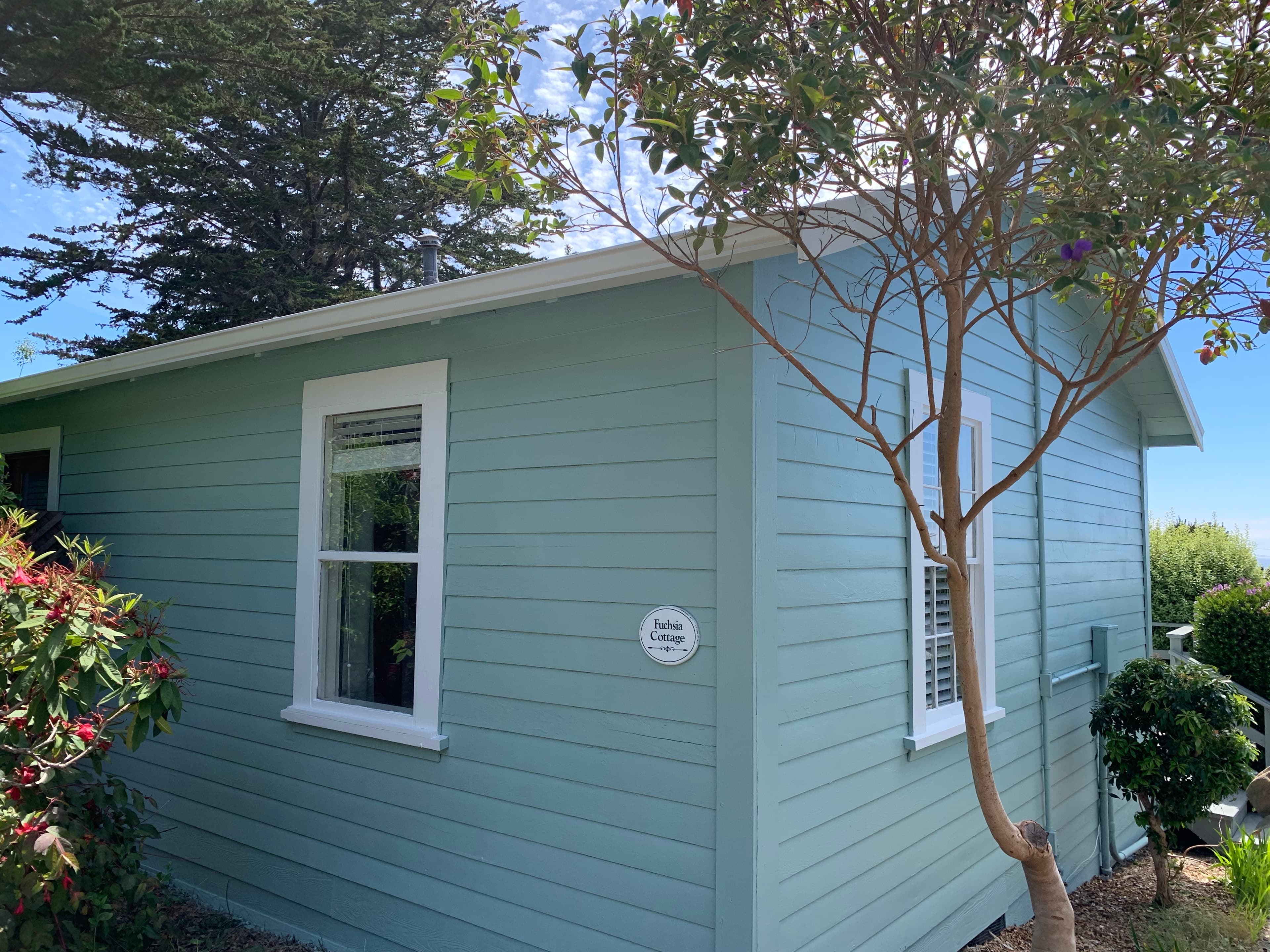 A small, light blue house with white trim and a white door.