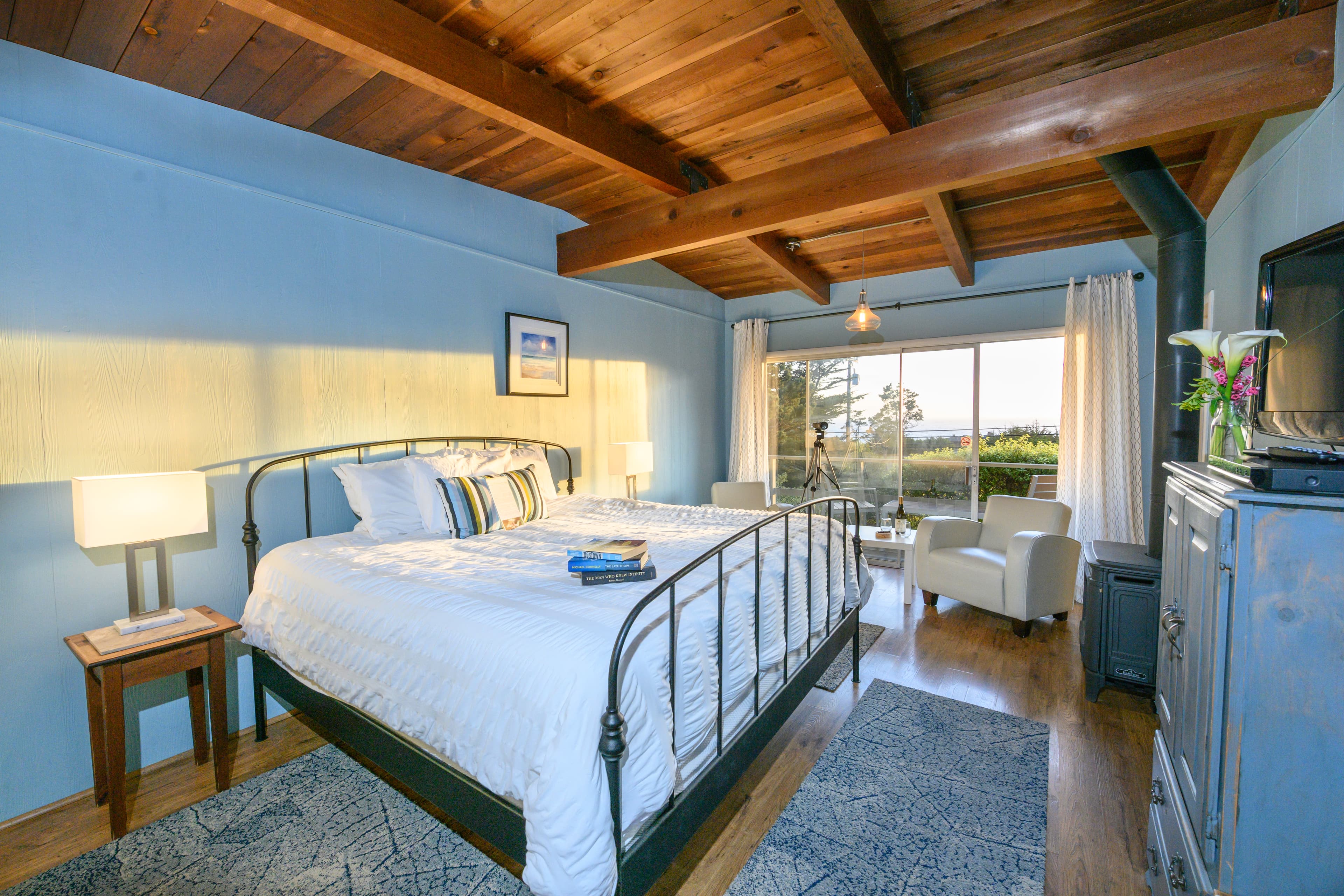 Anderson Valley bedroom with a king-sized bed, a wood-burning stove, and a view of the outdoors through large sliding glass doors.