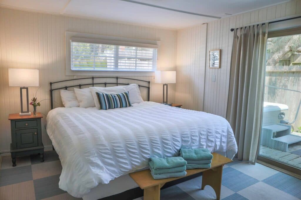 Bright bedroom featuring a queen-sized bed, decorative pillows, and sliding glass doors leading to an outdoor area.
