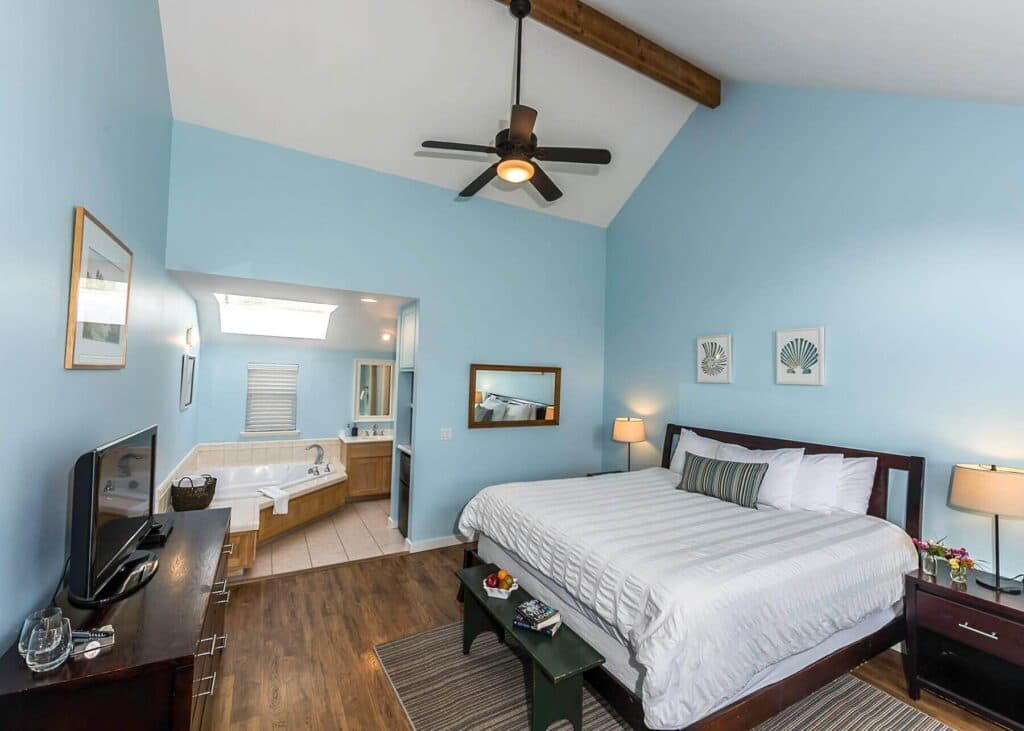 Bright, airy bedroom with a king-sized bed, a ceiling fan, and an adjoining bathroom.