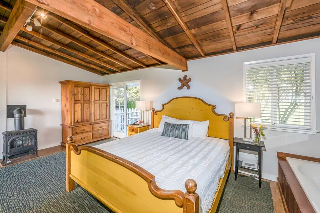 A cozy bedroom featuring a yellow bed, wooden furniture, and a rustic ceiling.