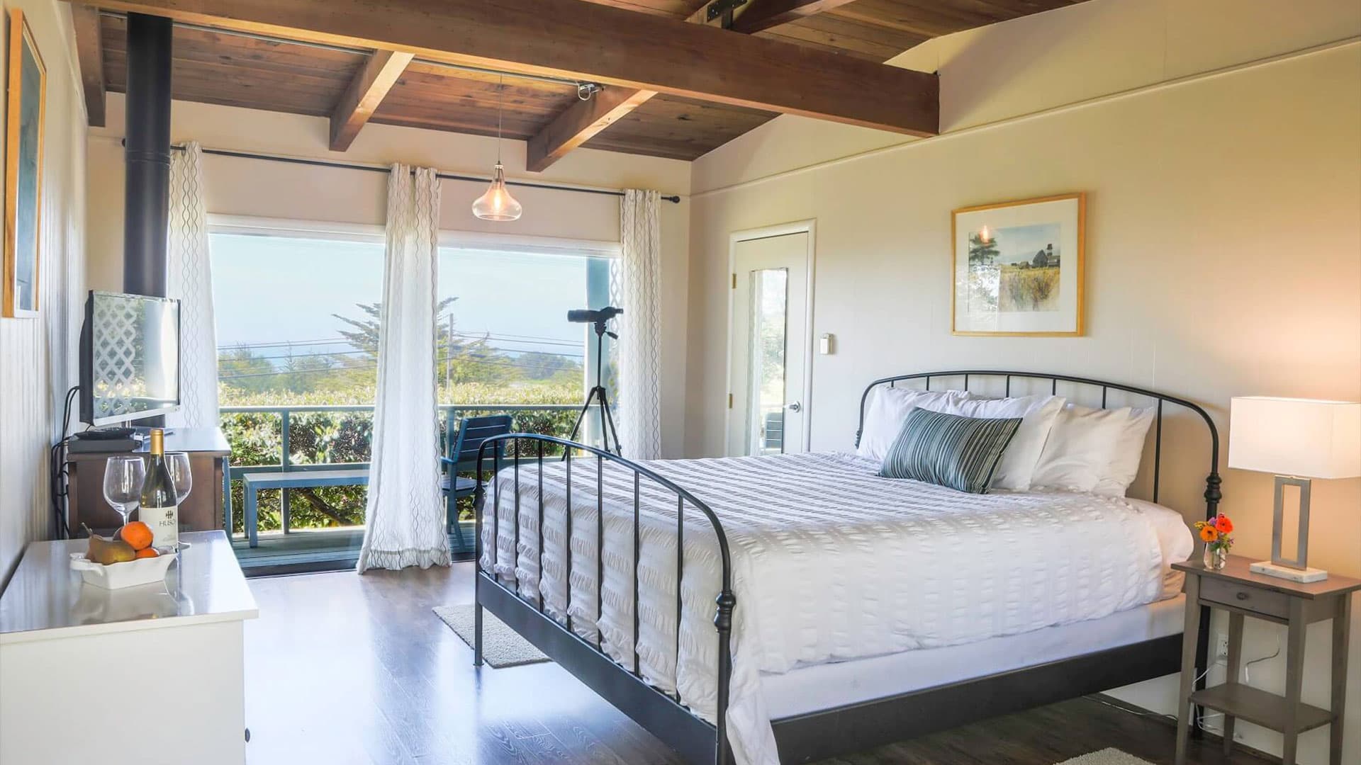 Cozy, warmly lit bedroom with rustic wooden beams and large windows overlooking landscape
