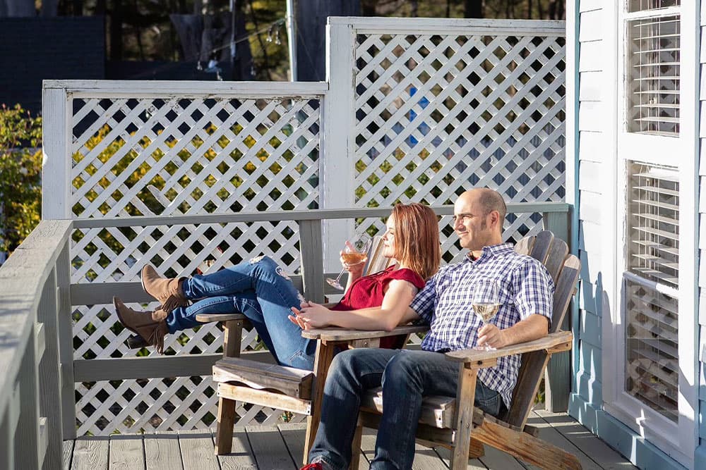 A couple relaxes on a porch, enjoying drinks in the sunshine.