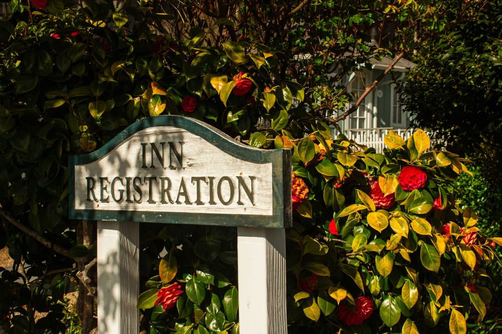 Sign reading "Inn Registration" surrounded by colorful foliage and flowers.